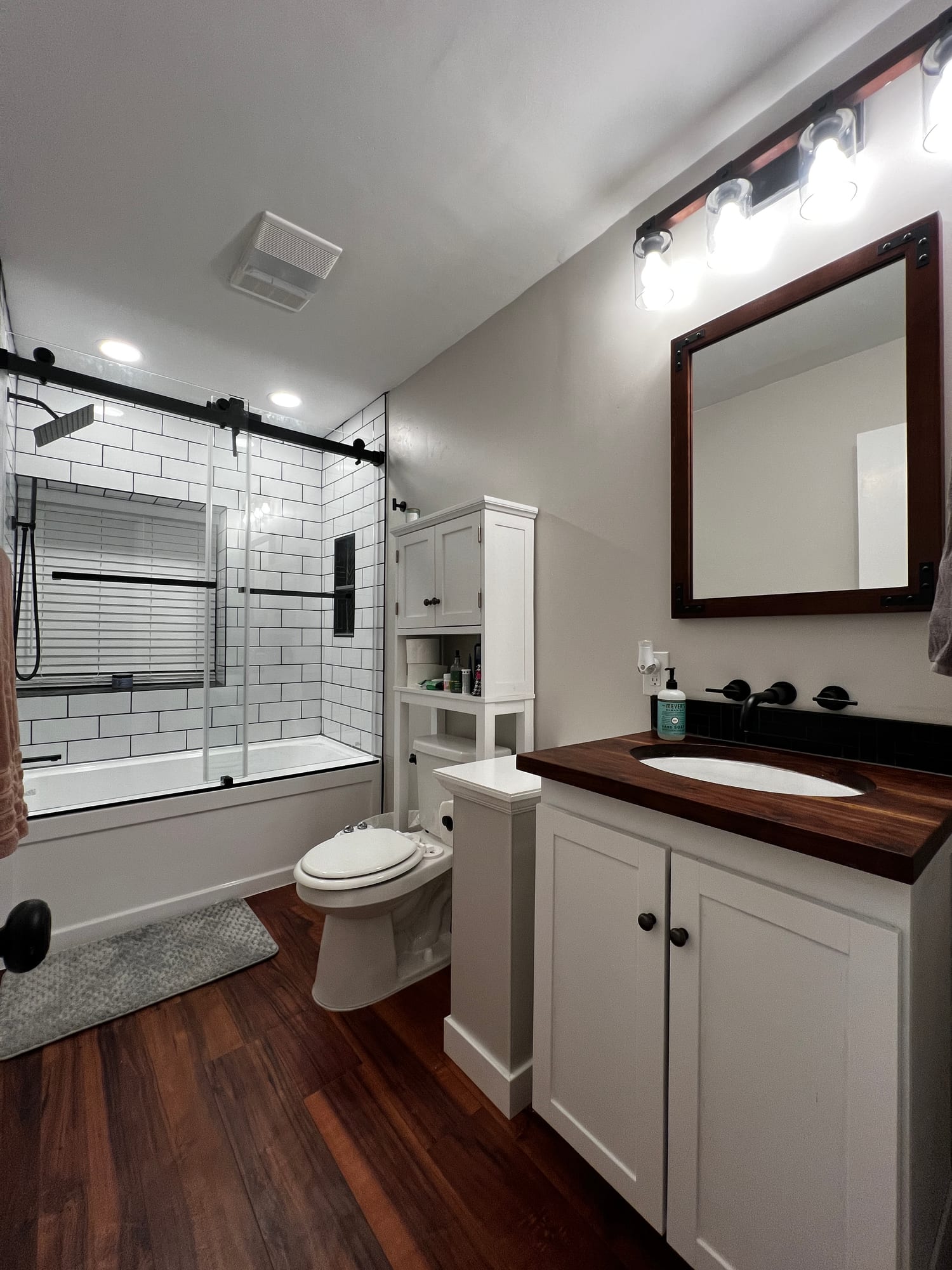 Finished bathroom with subway-tile shower and walnut vanity